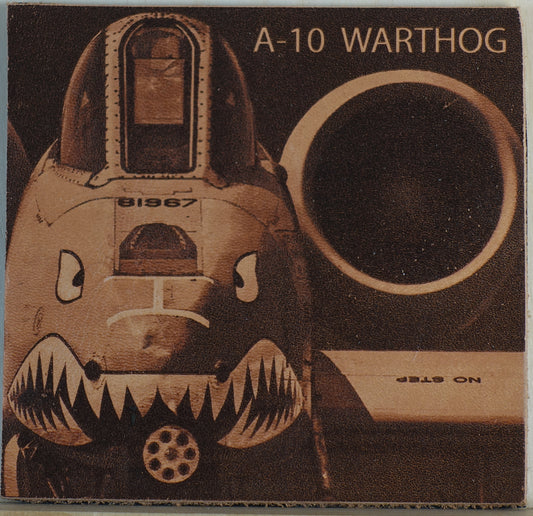 A 4"x4" patch with a composition from Michael Dean Barr of an A-10 Warthog lasered onto genuine leather featuring a stylized aircraft face with shark teeth, a large circular dark opening, and the text 'A-10 WARTHOG' at the top.